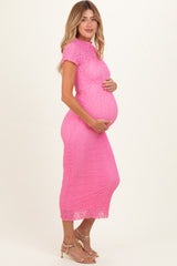 woman wearing a pink lace maternity dress and holding her baby bump