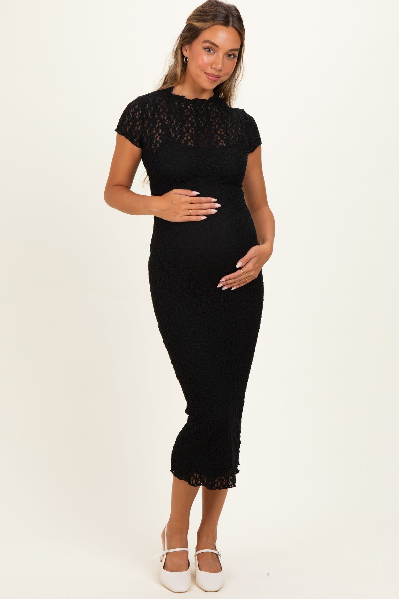 woman wearing a black lace maternity dress with short sleeves and holding her baby bump