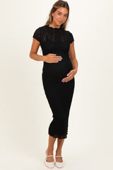 woman wearing a black lace maternity dress with short sleeves and holding her baby bump