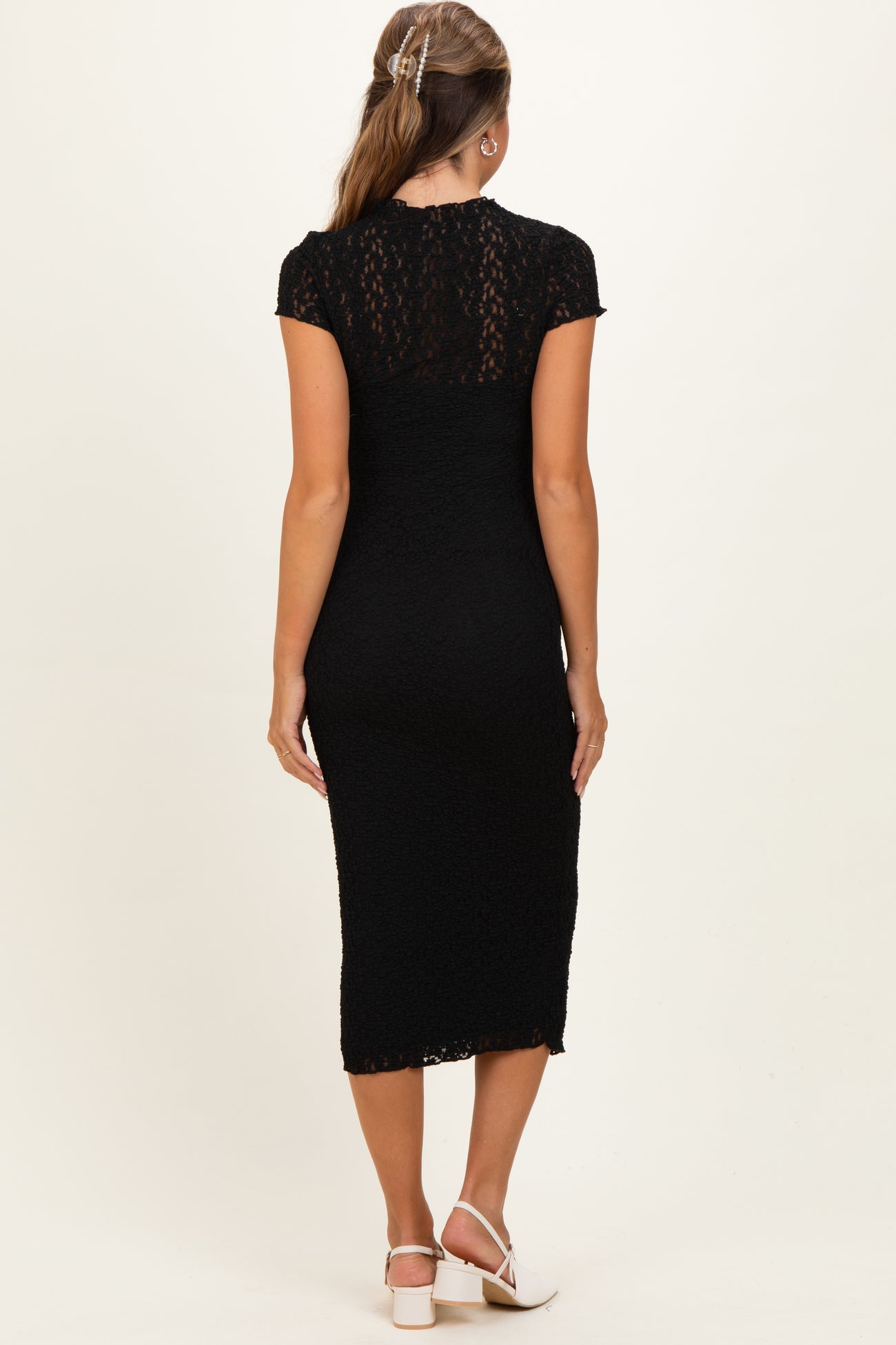 woman wearing a black maternity dress with short sleeves and a fitted silhouette, showing a stylish lace design from the back