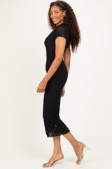 woman wearing a black lace midi dress with short sleeves and a fitted silhouette, posing sideways