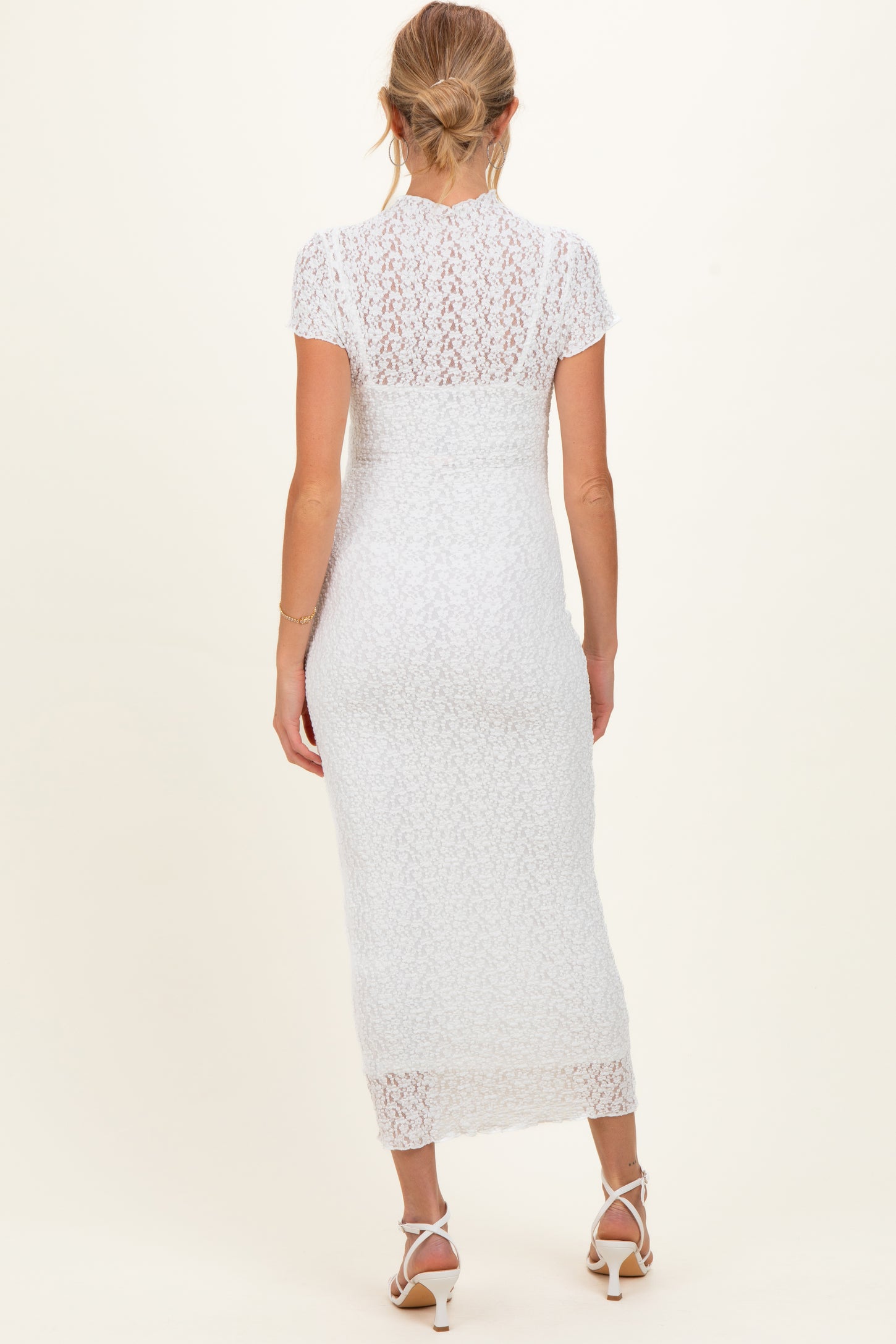 woman wearing a white lace maternity dress with a fitted silhouette and short sleeves, seen from the back