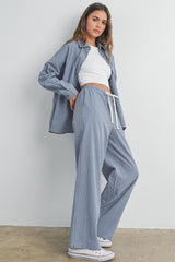 woman wearing a blue and white gingham check oversized shirt with matching pants and a white crop top