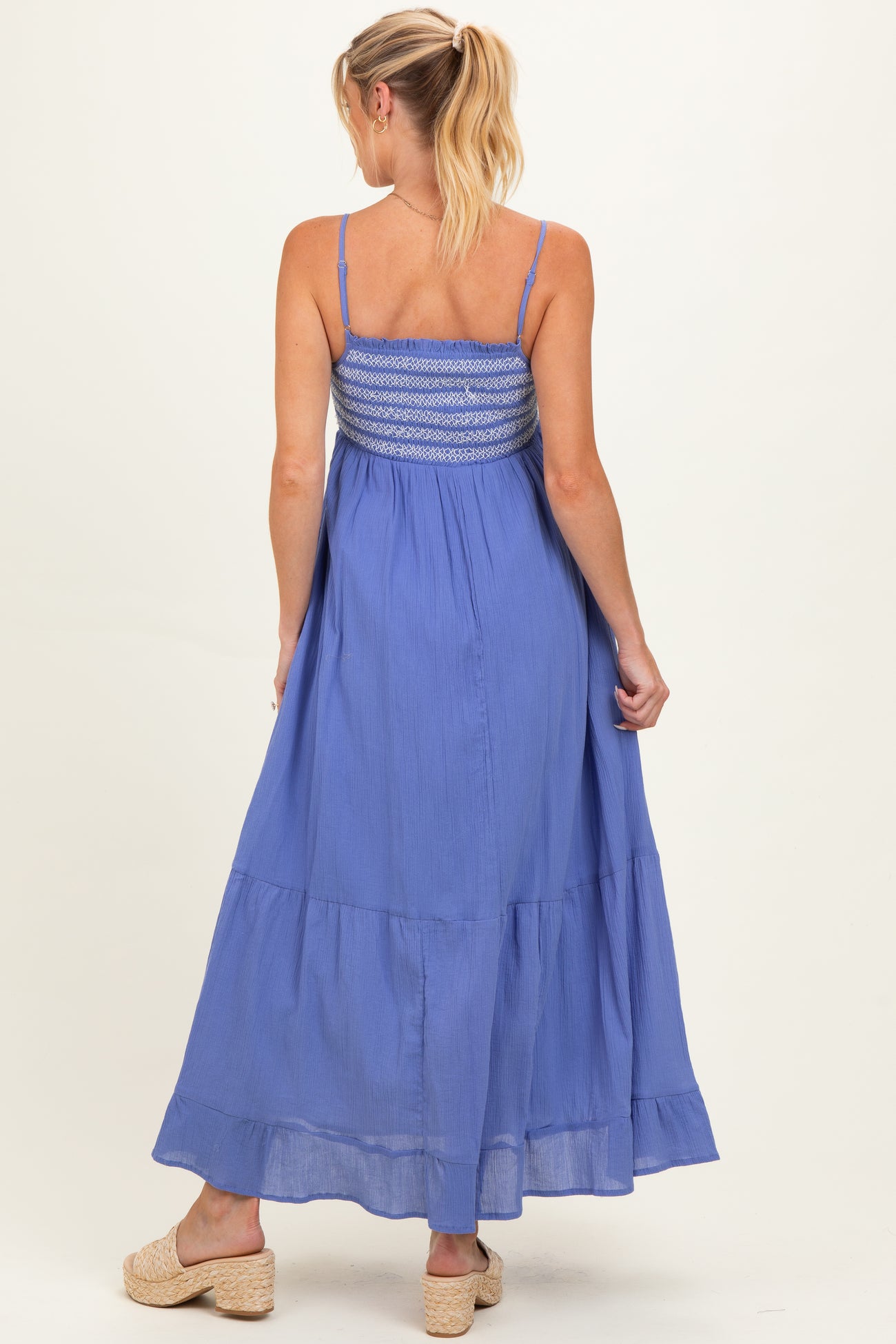 woman wearing a blue maternity maxi dress with a smocked bodice and tiered skirt, showing her back
