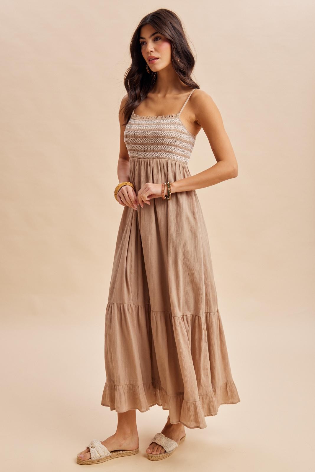 woman wearing a beige maxi dress with smocked bodice and tiered ruffle hem, styled with light sandals