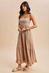 woman wearing a beige maxi dress with smocked bodice and tiered ruffle hem, styled with light sandals