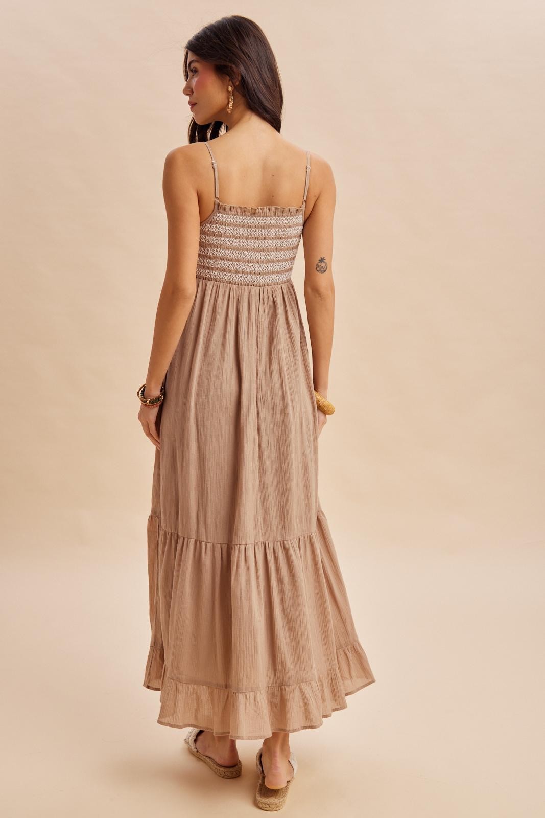 woman wearing a back view of a beige maxi dress with smocked bodice and tiered ruffle hem
