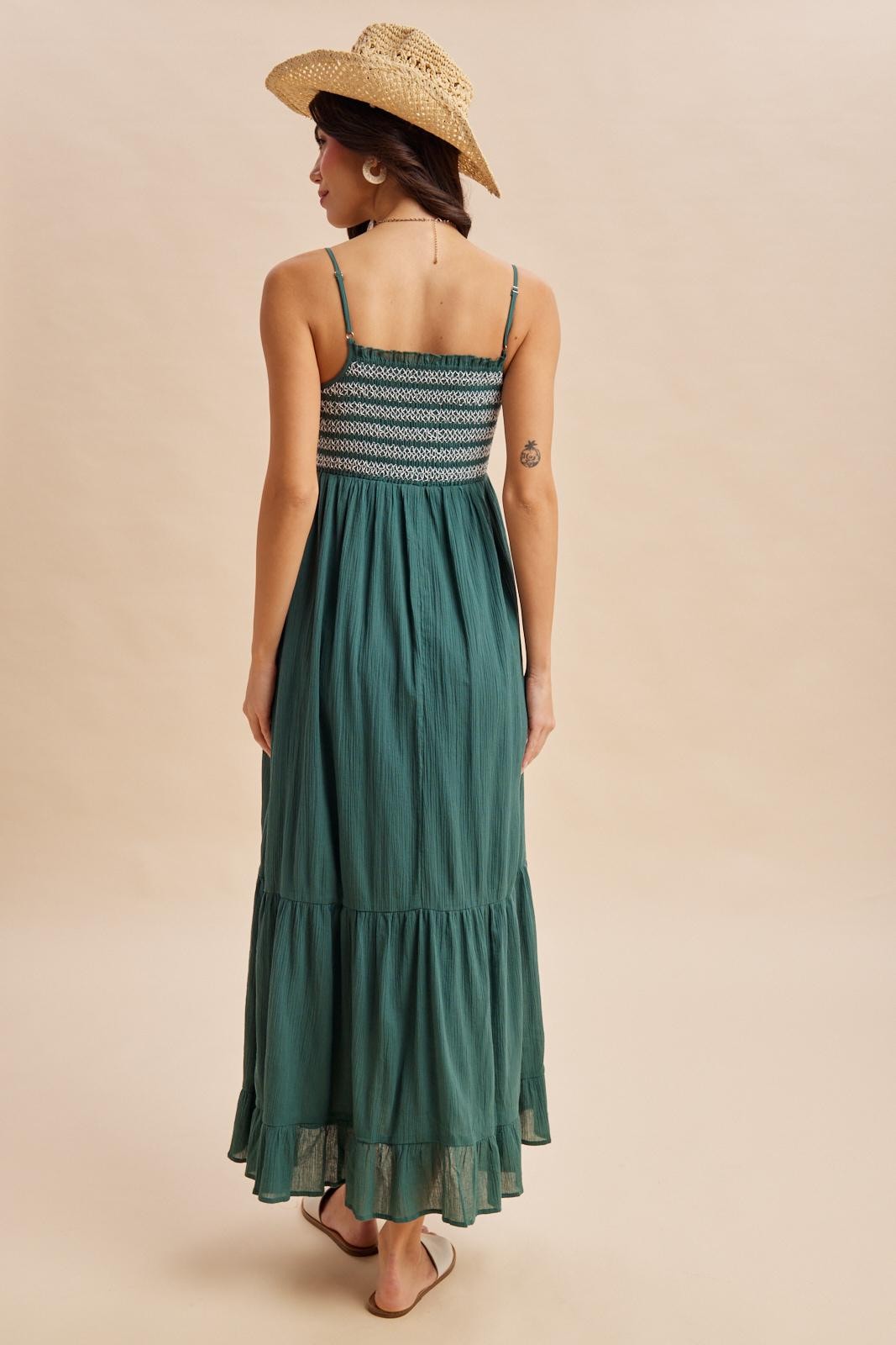 woman wearing a teal maxi dress with a smocked bodice and ruffled hem, styled with a straw hat