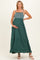 woman wearing a dark green maternity maxi dress with a smocked bodice and tiered skirt, holding her baby bump