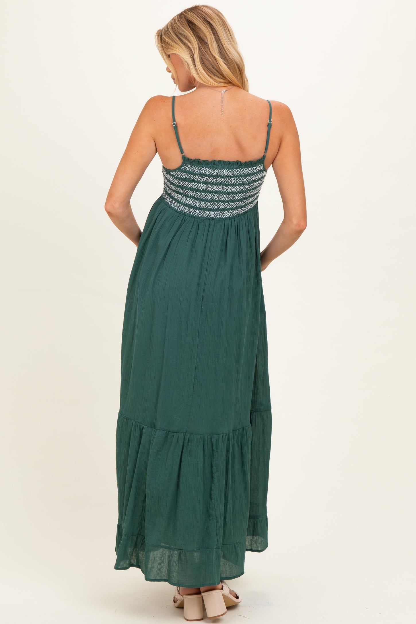 woman wearing a green maternity maxi dress with a smocked bodice and tiered skirt from the back