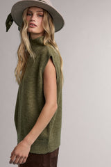 woman wearing a green sleeveless turtleneck sweater and a wide-brimmed hat