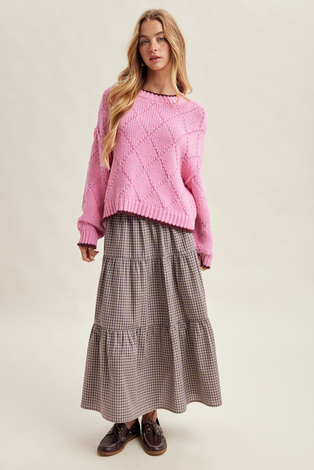 woman wearing a pink oversized knit sweater and a long plaid tiered maxi skirt with brown lace-up shoes