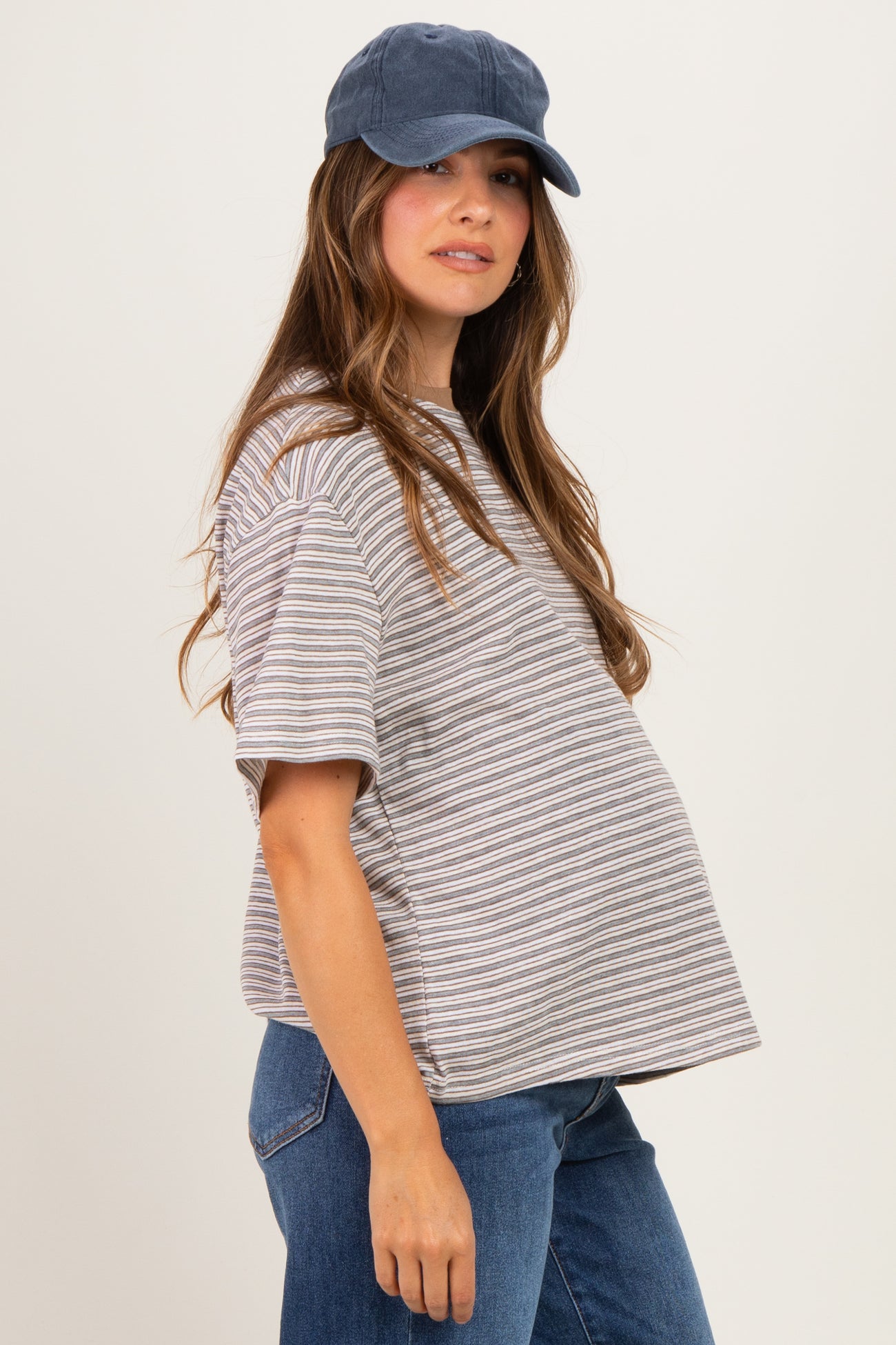 woman wearing a striped maternity t-shirt and blue cap, showing her baby bump with a relaxed fit and short sleeves