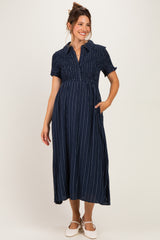 woman wearing a navy striped maternity dress with short sleeves and a collared neckline, holding her baby bump
