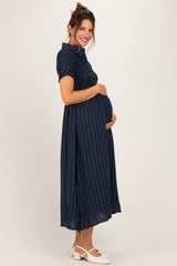 woman wearing a navy blue striped maternity dress with a fitted bodice, holding her baby bump and smiling