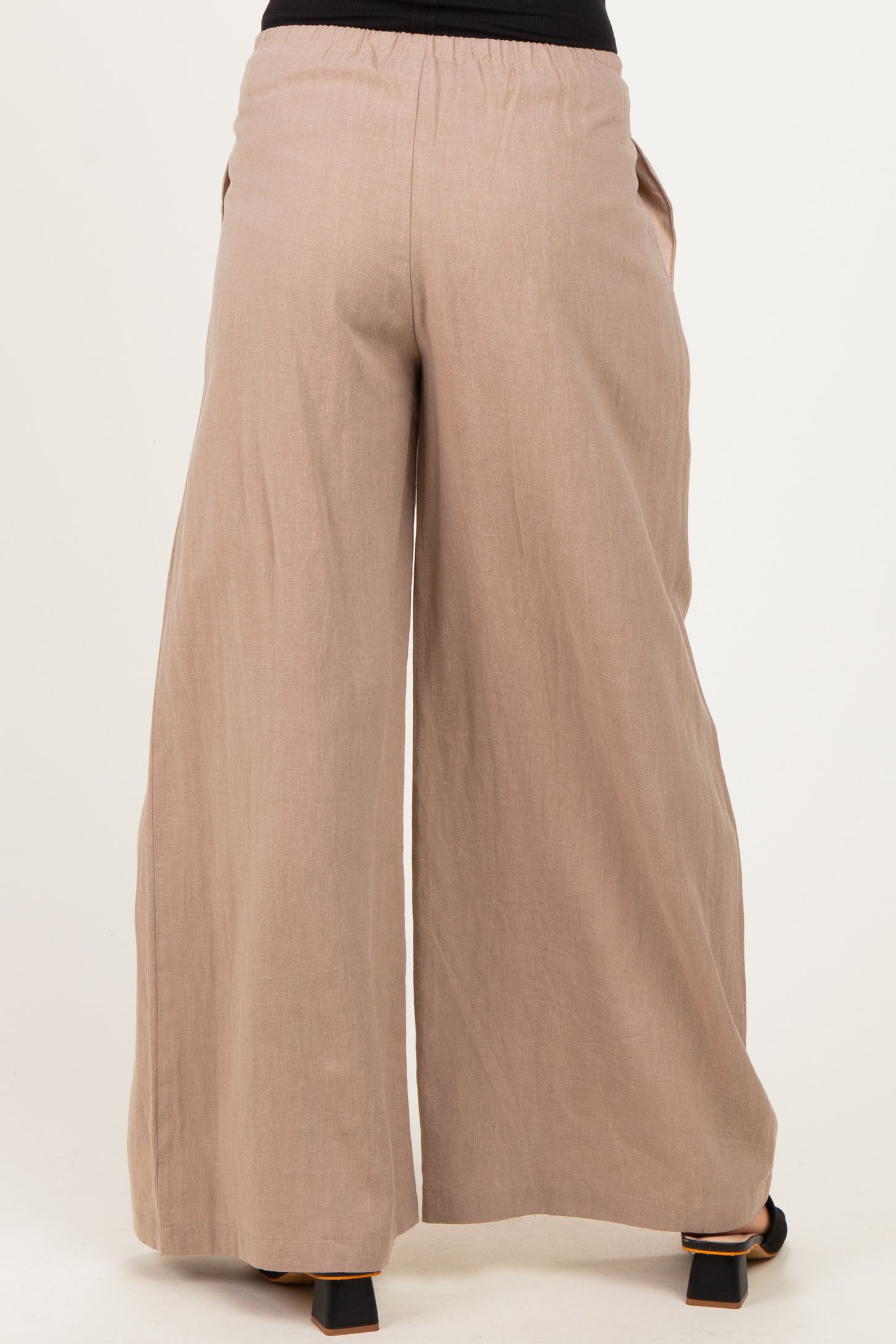 woman wearing light brown wide leg maternity pants with an elastic waistband and side pockets, viewed from the back