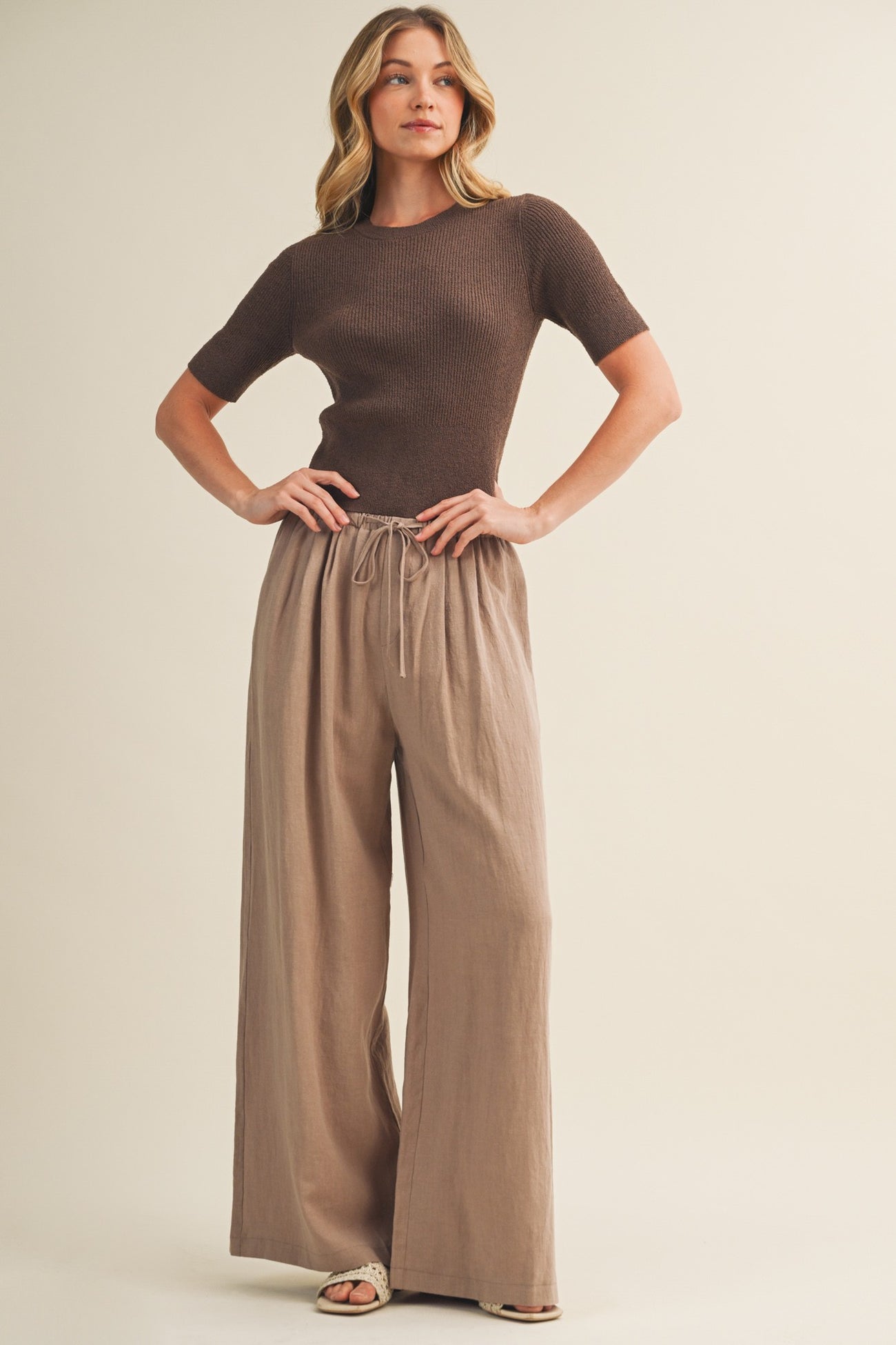 woman wearing a brown short sleeve knit top and tan wide-leg pants with a drawstring waist