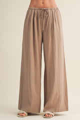woman wearing loose-fitting beige wide-leg pants with an elastic waistband and drawstring detail