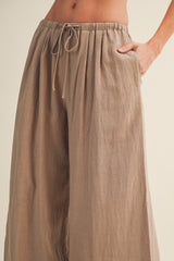 woman wearing taupe wide leg linen pants with an elastic waistband and drawstring details