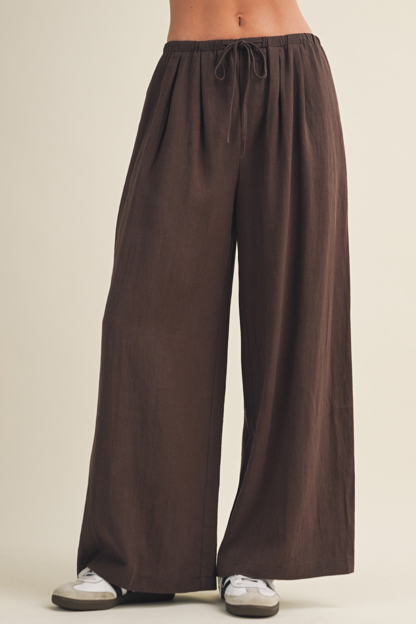 woman wearing brown wide-leg pants with a drawstring waist and pockets