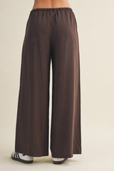 woman wearing brown wide-leg pants from the back with an elastic waistband and casual footwear