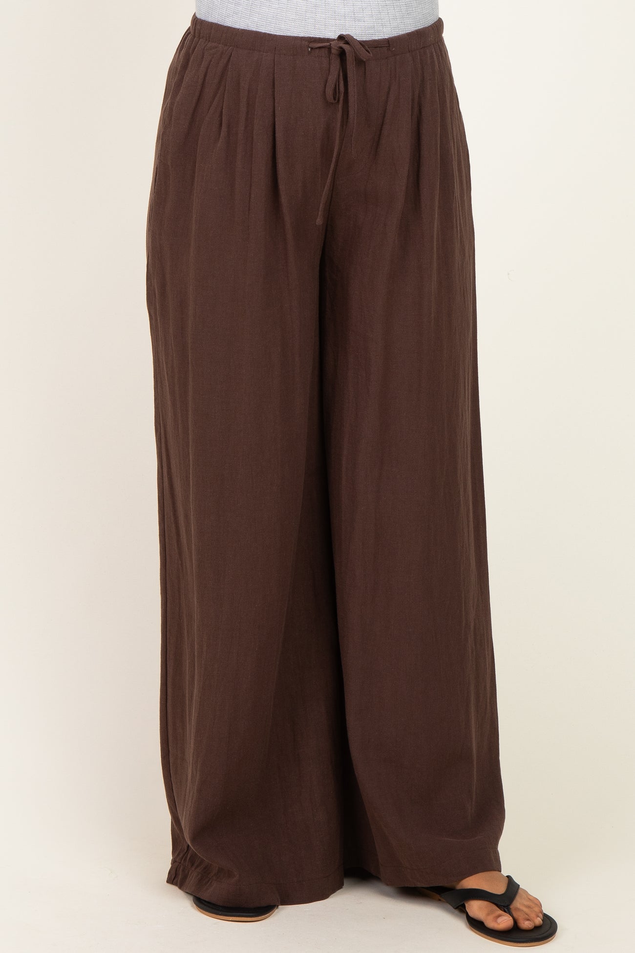 maternity wear brown wide-leg pants with drawstring waist and pleated details, model wearing them with sandals
