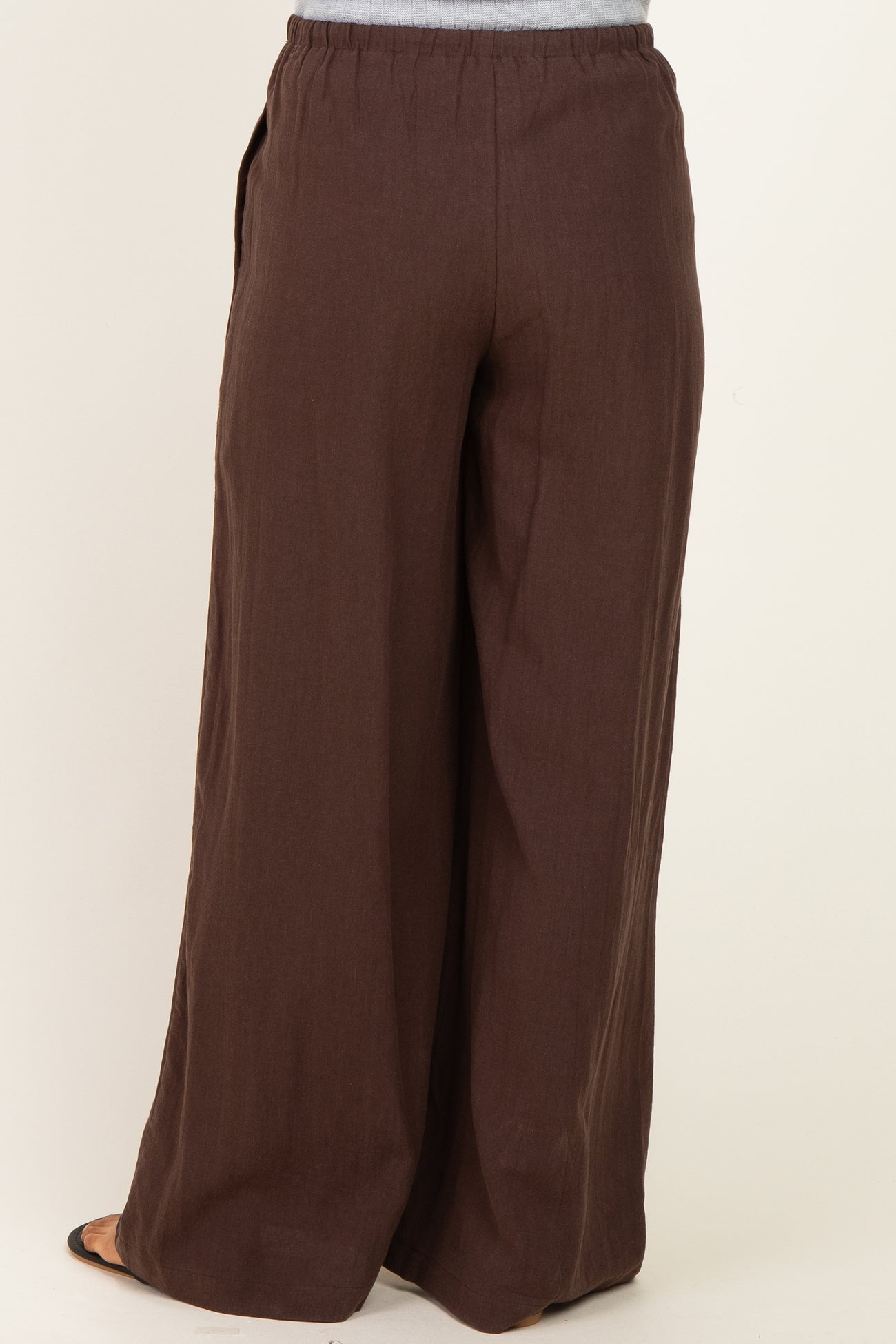 maternity wear brown wide leg pants with an elastic waistband and side pockets, shown from the back