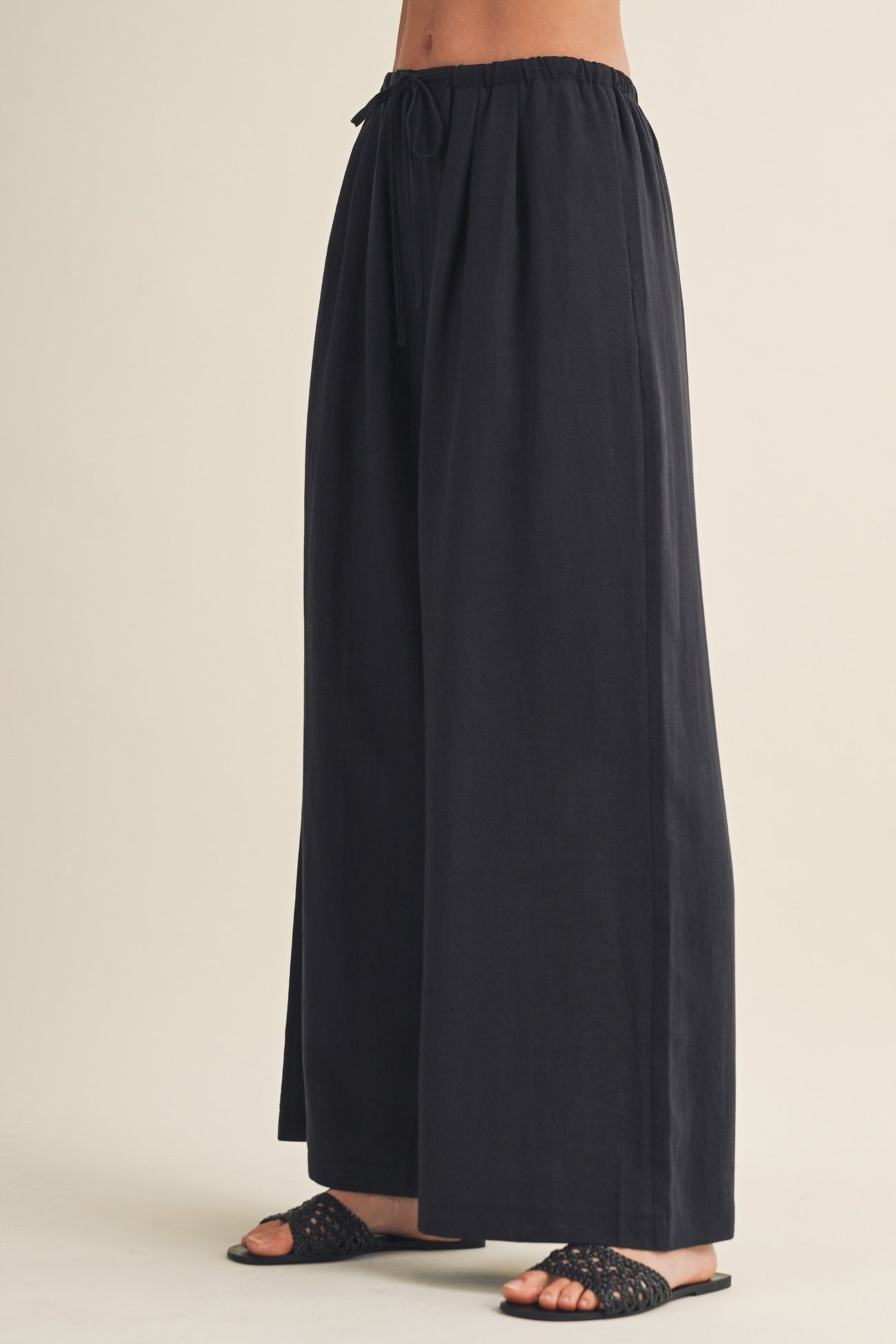 woman wearing black wide-leg pants with an elastic waistband and drawstring detail