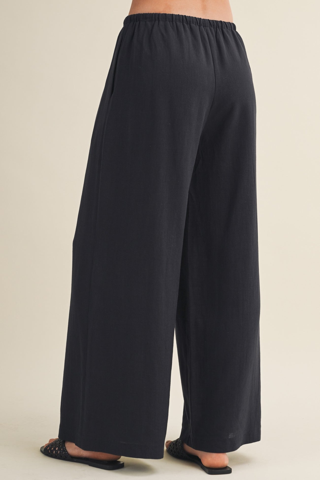 woman wearing black wide-leg pants with an elastic waistband, shown from the back
