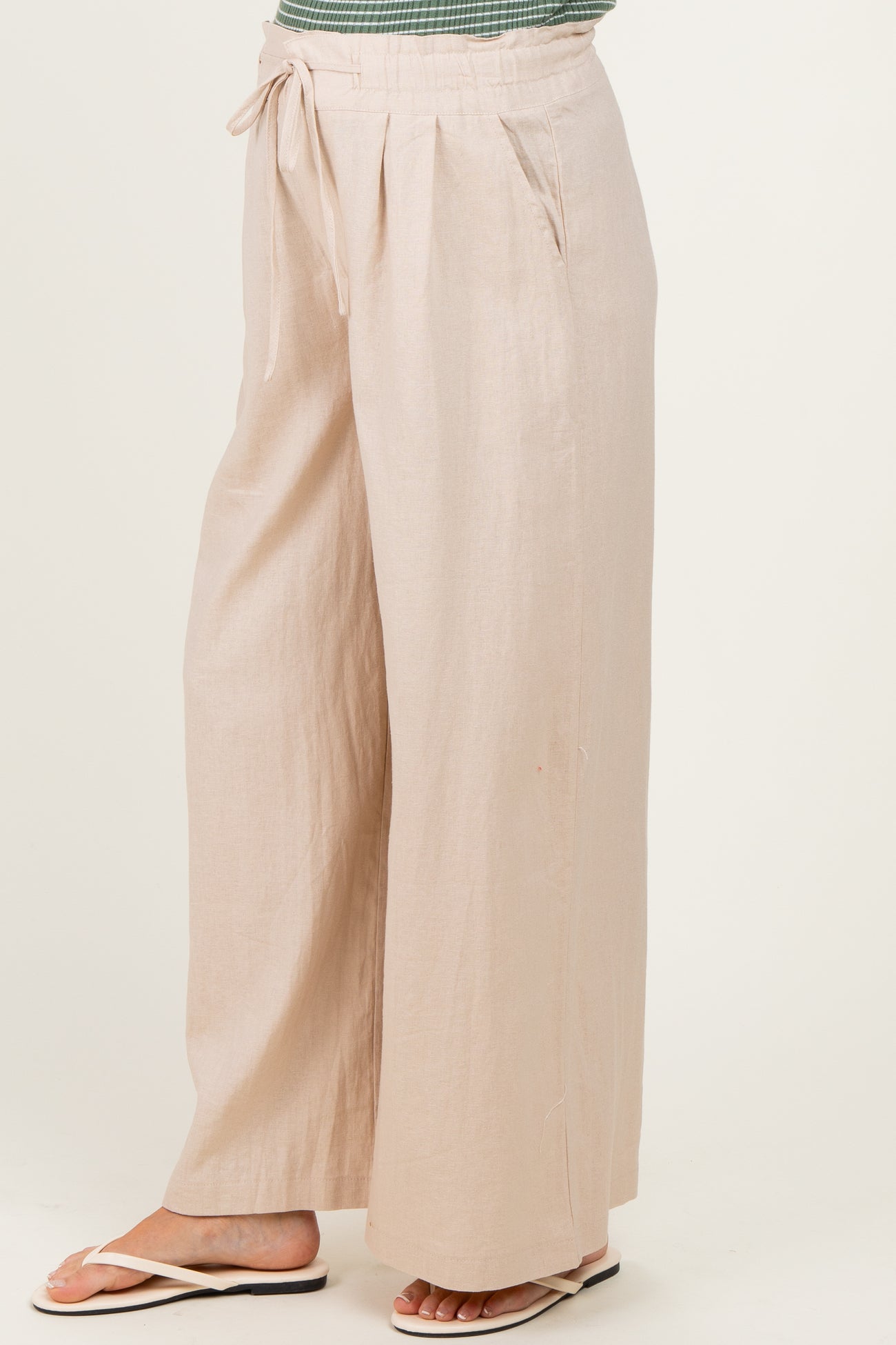 woman wearing light beige wide-leg maternity pants with a drawstring waist and side pockets