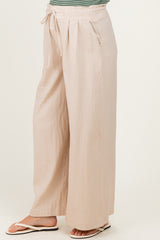 woman wearing light beige wide-leg maternity pants with a drawstring waist and side pockets