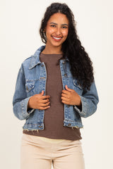 woman wearing a light blue denim maternity jacket over a brown top, smiling at the camera