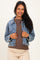 woman wearing a light blue denim maternity jacket over a brown top, smiling at the camera
