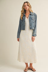woman wearing a white midi dress with floral details and a denim jacket, styled with flip-flops