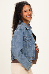 woman wearing a light blue maternity denim jacket and holding her baby bump