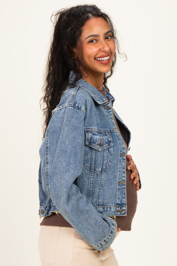 woman wearing a light blue maternity denim jacket and holding her baby bump