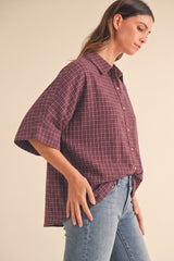 woman wearing a maroon checkered oversized button-up shirt with relaxed sleeves and paired with light blue jeans