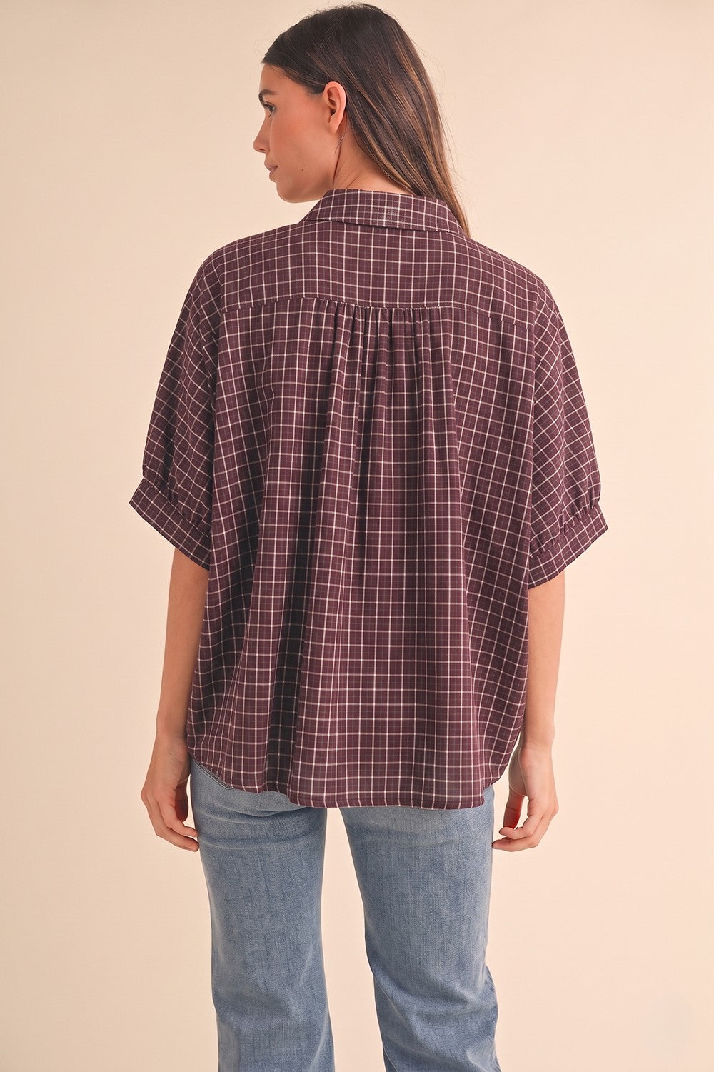 woman wearing a maroon checkered short sleeve shirt with a relaxed fit and back pleat detail