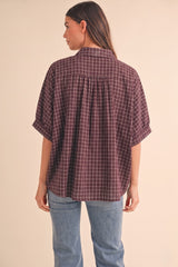 woman wearing a maroon checkered short sleeve shirt with a relaxed fit and back pleat detail