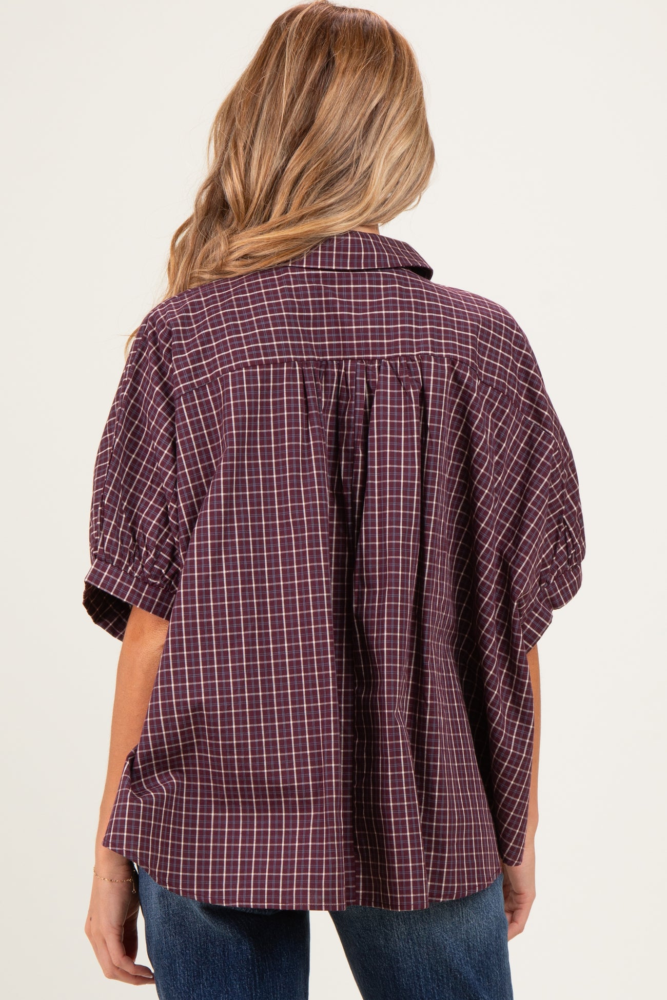 woman wearing a maroon checkered maternity shirt with a relaxed fit and back pleat detail