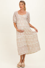 woman wearing a floral maternity dress with puff sleeves and tiered skirt, holding her baby bump