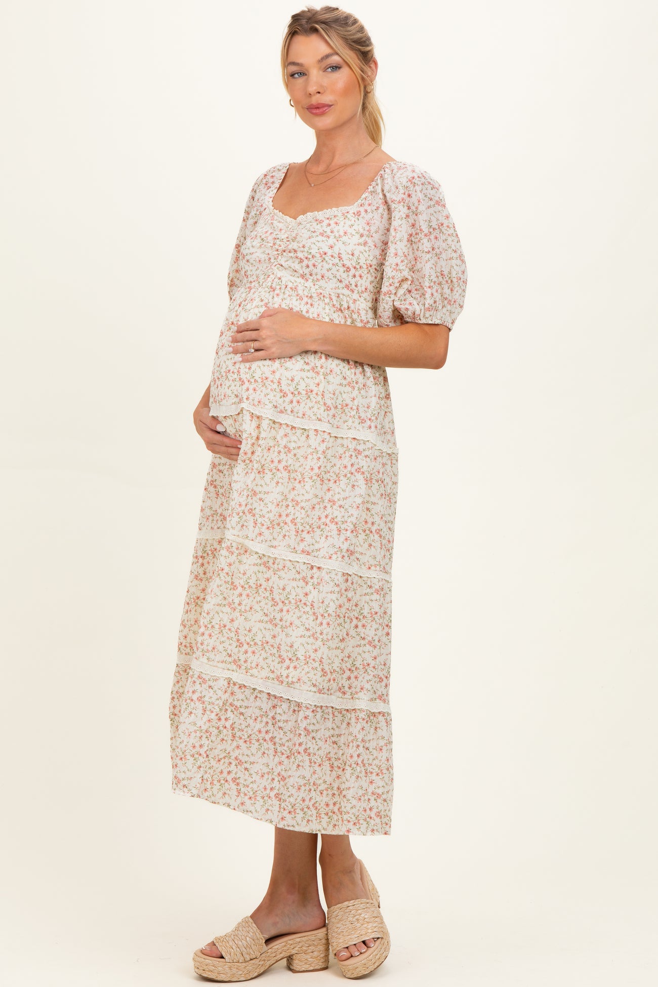 woman wearing a floral print maternity maxi dress with tiered detailing and a visible baby bump
