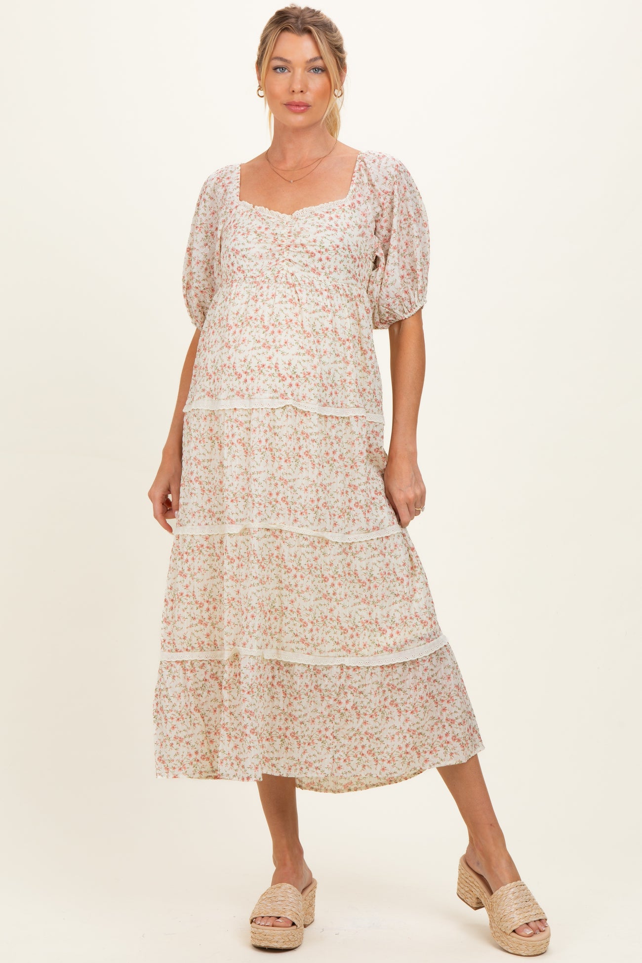 woman wearing a floral print maternity dress with puff sleeves and tiered skirt, showcasing her baby bump