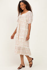 woman wearing a floral print midi dress with puff sleeves and a tiered skirt, smiling against a neutral background