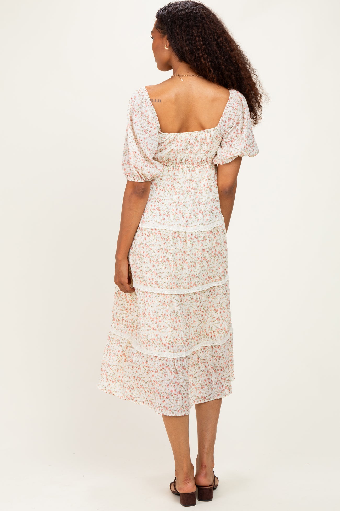 woman wearing a floral midi dress with puff sleeves and ruffle details, showing the back view