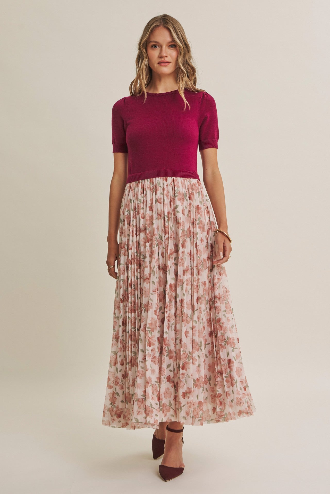 woman wearing a burgundy short sleeve top and a floral maxi skirt with pleats