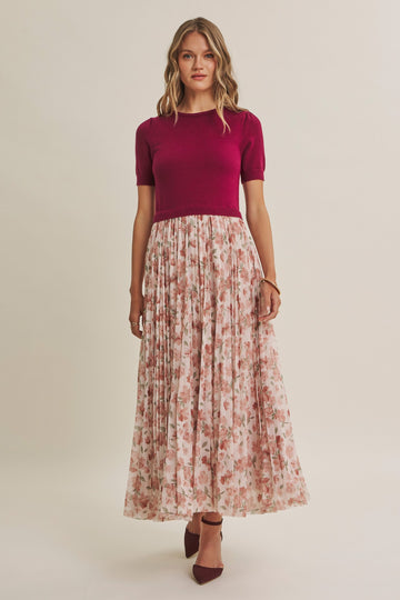 woman wearing a burgundy short sleeve top and a floral maxi skirt with pleats