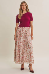 woman wearing a fuchsia short sleeve top and a long floral skirt with pleats, paired with red high heels