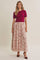 woman wearing a fuchsia short sleeve top and a long floral skirt with pleats, paired with red high heels