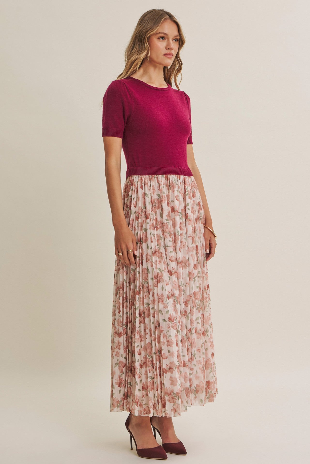 woman wearing a fuchsia short sleeve top and a floral pleated maxi skirt with heeled shoes